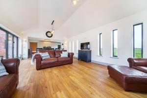 a living room with two leather couches and a kitchen at EASTFIELD HOUSE in Whissonsett