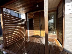 a wooden front porch of a house with a glass door at AOBA Hakuba self-contained home in Hakuba