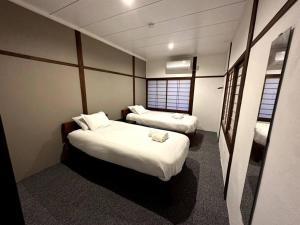 a hotel room with two beds and two windows at AOBA Hakuba self-contained home in Hakuba