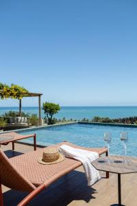 a table and chairs next to a swimming pool at Mansão Vista de 180º para Mar na Rota dos Milagres in Passo de Camarajibe