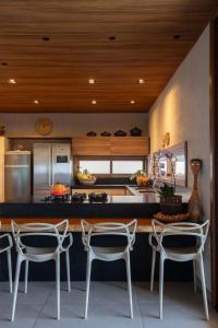 a kitchen with a counter and some chairs in it at Mansão Vista de 180º para Mar na Rota dos Milagres in Passo de Camarajibe