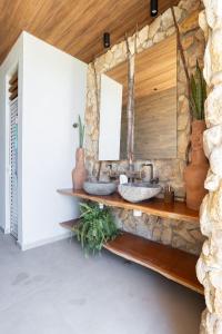 a bathroom with two sinks and a stone wall at Mansão Vista de 180º para Mar na Rota dos Milagres in Passo de Camarajibe