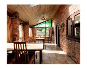 una sala da pranzo con tavoli, sedie e un muro di mattoni di Self Check-In Rooms at The Three Horseshoes Inn a Bromyard