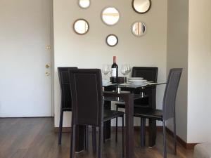 a dining room table with black chairs and a bottle of wine at Lindo y acogedor departamento en Bellavista in Santiago