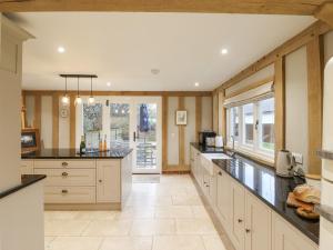 a large kitchen with white cabinets and black counter tops at Lodge Cottage in Harwich