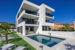 a white house with a swimming pool in front of it at Deluxe villa with heated pool, whirpool, sea view near beautiful beach III - by Traveler tourist agency Krk ID 2402 in Krk