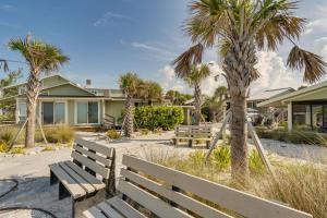 eine Parkbank vor einem Haus mit Palmen in der Unterkunft Manasota Key Vacation Rental with Beach Access! in Englewood