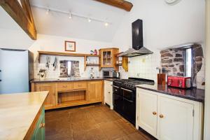 uma cozinha com armários de madeira e um forno de fogão preto em Cwm Pelved is a large 6 bedroom holiday home close to Hay on Wye - with incredible views em Hereford
