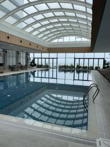 duży basen w budynku ze szklanym sufitem w obiekcie Poseidon Apartments Batumi w mieście Batumi