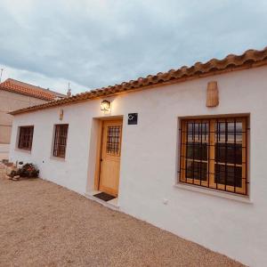 ein weißes Haus mit Holztüren und einer Auffahrt in der Unterkunft Casa Vacaciones ALMADRABA CABO COPE in Águilas