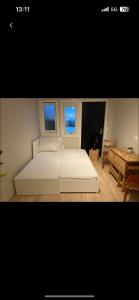 een wit bed in een kamer met 2 ramen bij Liten koselig hybelleilighet for 1 til 2 personer - sentral beliggenhet og gunstig pris in Tromsø