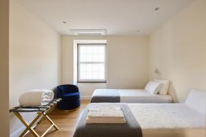 1 dormitorio con 2 camas, silla y ventana en FLH Porto Clérigos Luxury Apartments en Oporto