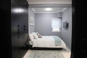 a bedroom with a bed with white sheets and a rug at Trendy Cottage Hideaway in Cape Town
