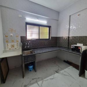 uma cozinha suja com um lavatório e uma janela em Katke's HomeStay. em Sholapur