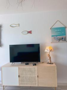 einen Fernseher auf einem Schrank mit Lampe in der Unterkunft Au Ti Menhir * 2 à 4 vacanciers * Piscine * WIFI in Carnac