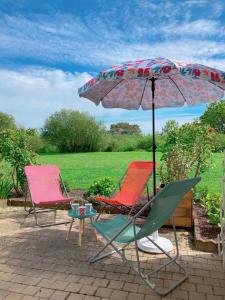 zwei Stühle und ein Regenschirm auf einer Terrasse in der Unterkunft Au Ti Menhir * 2 à 4 vacanciers * Piscine * WIFI in Carnac