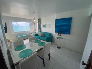 sala de estar con mesa y sofá azul en Vista incrível com Pé na areia à beira-mar - Apto 901, en Maceió