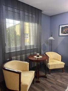 a living room with a table and chairs and a window at Hotello Apartmanház és Panzió in Zalaegerszeg