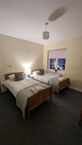 a bedroom with two beds and a window at The Cosy Beech in Lisnaskea