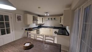a kitchen with white cabinets and a wooden table at Cosy Fermanagh Home - The Cosy Beech in Lisnaskea