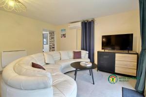a living room with a white couch and a flat screen tv at Au charme des bois in Plouhinec