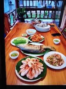 Bang Yan Rimlay في كو ياو نوي: طاولة خشبية مع أطباق من المأكولات البحرية وغيرها من المواد الغذائية