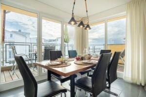 uma sala de jantar com mesa, cadeiras e janelas em Strandpark-Grossenbrode-Haus-Windrose-Wohnung-13 em Grossenbrode