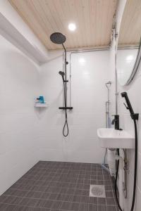 La salle de bains blanche est pourvue d'un lavabo et d'une douche. dans l'établissement Huoneisto Rovakatu 27 A7, à Rovaniemi