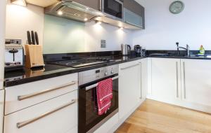 een keuken met witte kasten en een fornuis met oven bij Gorgeous 2BR Apartment with City Views in Leeds