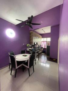 una sala da pranzo con pareti viola e tavolo e sedie di Homestay ShimahJay Telok Mas Melaka a Malacca