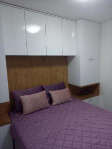a bedroom with a purple bed with white cabinets at SM apartman in Bijeljina