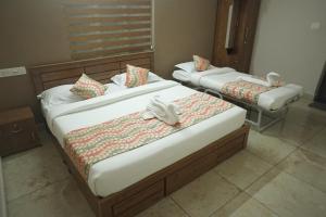 two beds in a hotel room with towels on them at Luxe Hotel - Rooms & Villas Wayanad in Wayanad
