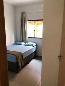 a small bedroom with a bed and a window at Casa primavera in Pirenópolis