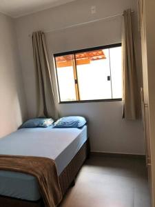 a small bedroom with a bed and a window at Casa primavera in Pirenópolis