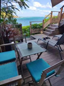 eine Terrasse mit Stühlen, einem Tisch und einem Sonnenschirm in der Unterkunft KARETS VIEW les pieds dans l eau - feet in water in Marigot