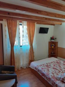 Schlafzimmer mit einem Bett, einem TV und Vorhängen in der Unterkunft Casa Geo in Breaza de Jos