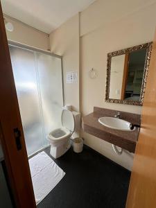 a bathroom with a toilet and a sink and a mirror at Condall Palace Hotel in Nova Prata