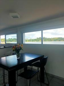 a table with a vase of flowers and two windows at Location les pieds dans l'eau in Vannes