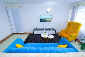 un salon avec un canapé bleu et un fauteuil jaune dans l'établissement Betty's staycation Thika road, à Nairobi