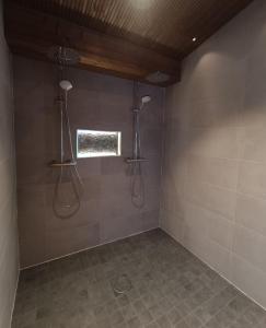 a bathroom with two shower heads and a window at Mökki ulkoporealtaalla in Uurainen