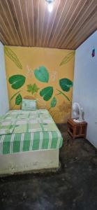Finca Mamacita في Rusia: غرفة نوم مع سرير مع أوراق خضراء مدهونة على الحائط