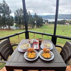 une table en bois avec des assiettes de nourriture dans l'établissement Hospedaje cabaña Guatavita Finca las Acacias, à Guatavita