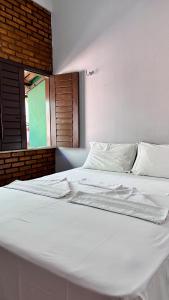 a large white bed in a room with a window at Suítes Green Village Flecheiras in Flecheiras