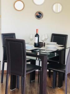una mesa de comedor con sillas negras y una botella de vino en Lindo y acogedor departamento en Bellavista, en Santiago