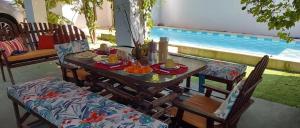 uma mesa e cadeiras com comida ao lado de uma piscina em Casa Tudo Azul em Amontada