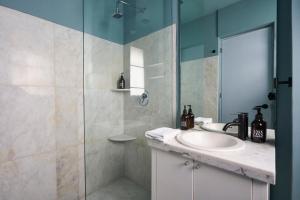 W łazience znajduje się umywalka i przeszklony prysznic. w obiekcie AmazINN Places La Condesa Roma w mieście Meksyk