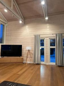 d'un salon avec une télévision à écran plat et des fenêtres. dans l'établissement Grand Hideout Lake Päijänne, à Vääksy