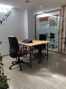 un ufficio con tavolo in legno, sedie e finestra di Urban rest zone and coworking ad Arrecife
