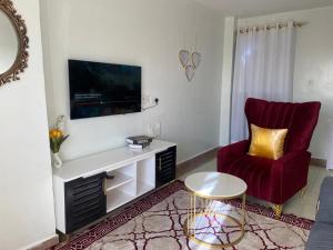 a living room with a red chair and a tv at Garden estate Thika road furnished home in Nairobi