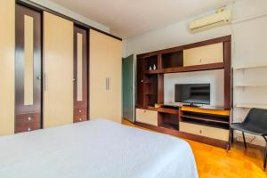 um quarto com uma cama, uma televisão e uma cadeira em Apto com Wi Fi proximo ao centro Porto Alegre RS em Porto Alegre